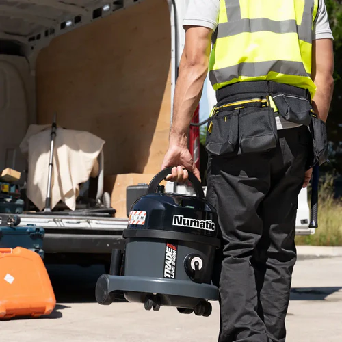Worker carrying Numatic TRM240H dust extraction vacuum using top handle