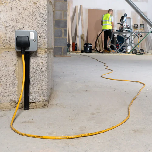 Numatic TRM240H connected with 10 metre hi-vis power cable on construction site